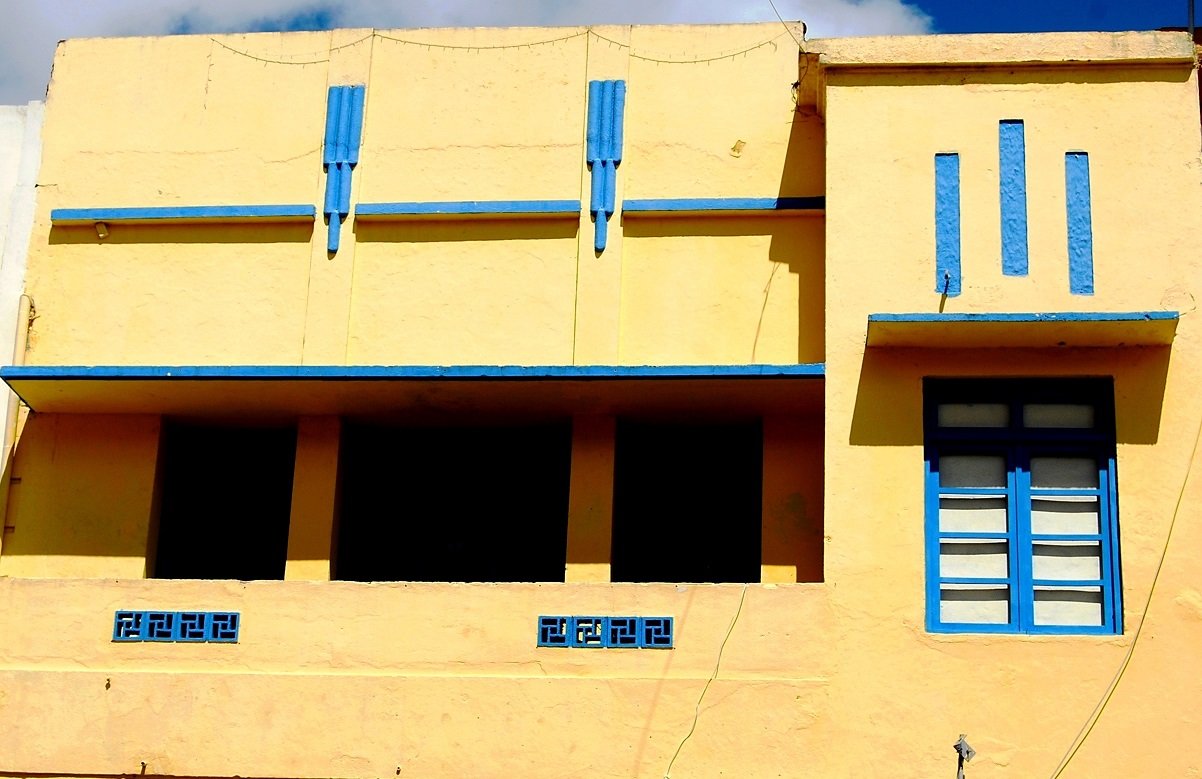 Fachada Art Déco amarela no centro de Campina Grande, com frisos geométricos e coroamento escalonado.