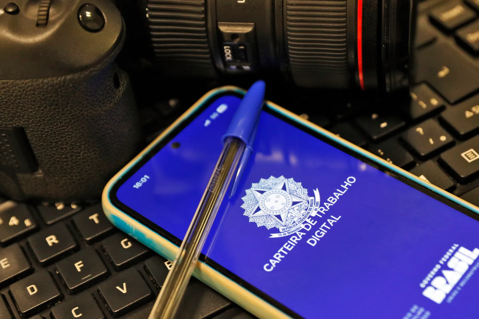 Celular exibe a tela da Carteira de Trabalho Digital, com o brasão da República, sobre um teclado.
