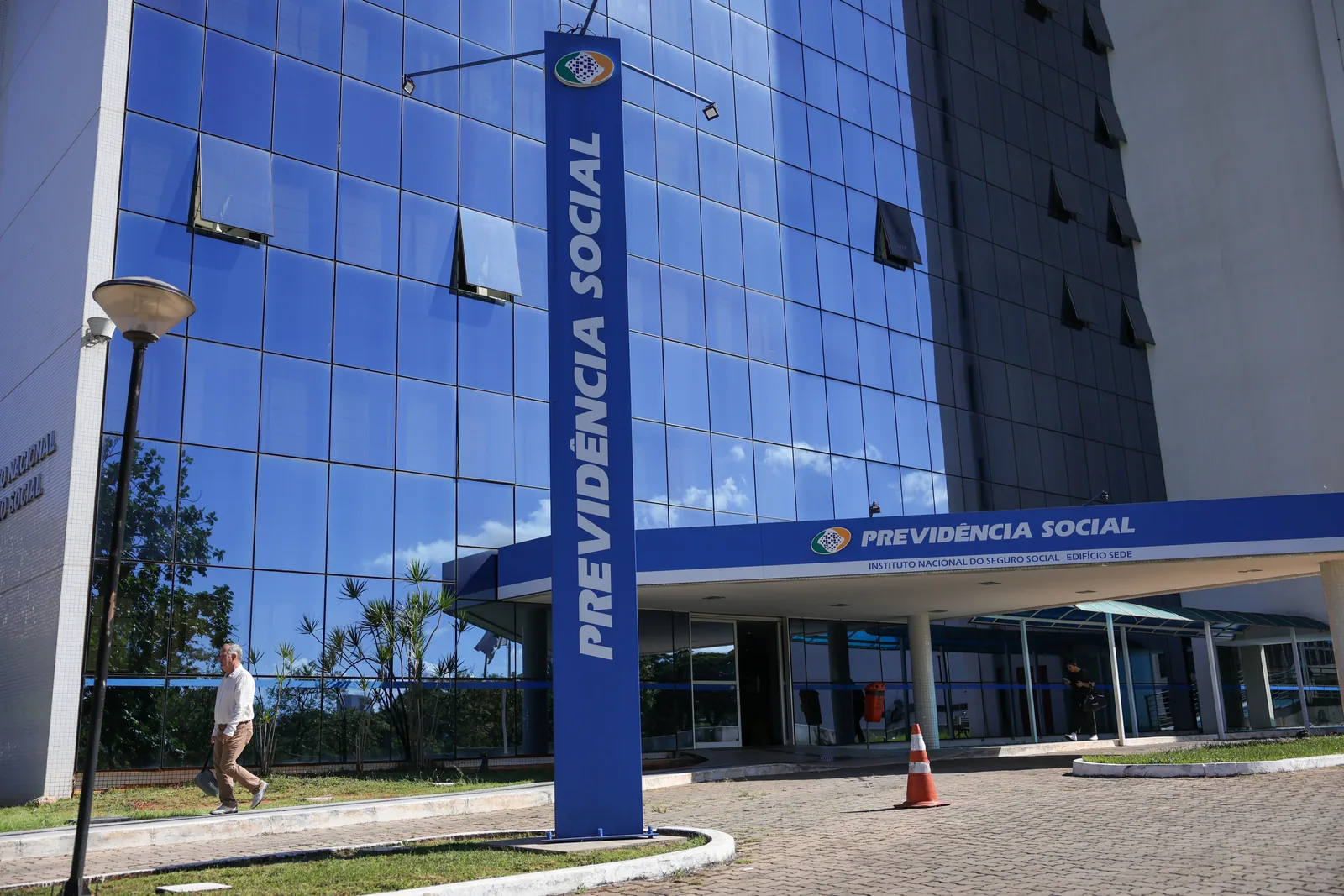 Fachada espelhada da sede da Previdência Social, com o letreiro azul do INSS na entrada