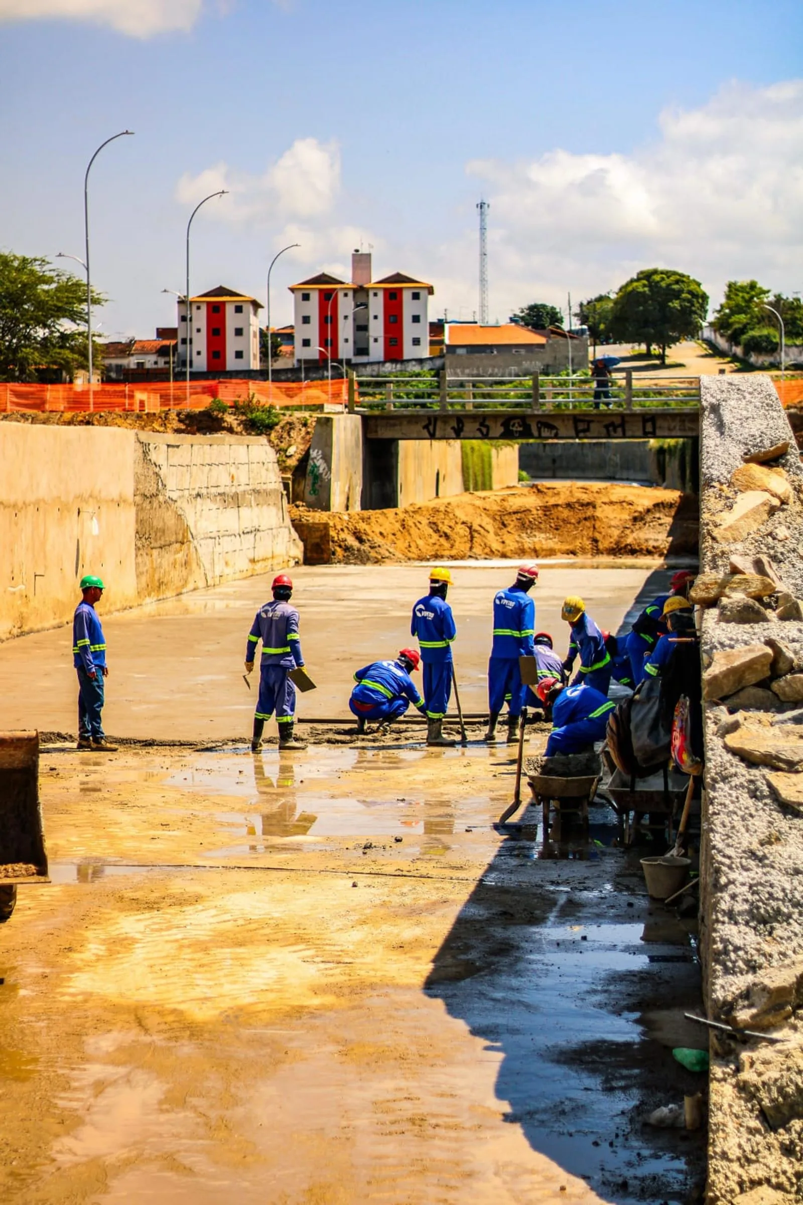 Operários trabalham no leito concretado do Canal de Bodocongó, sob a ponte, em Campina Grande