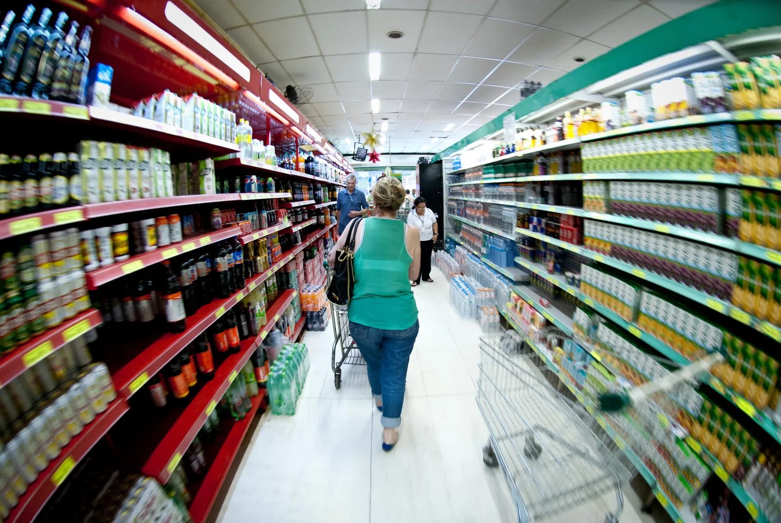 Corredor de supermercado com prateleiras lotadas de alimentos e bebidas.
