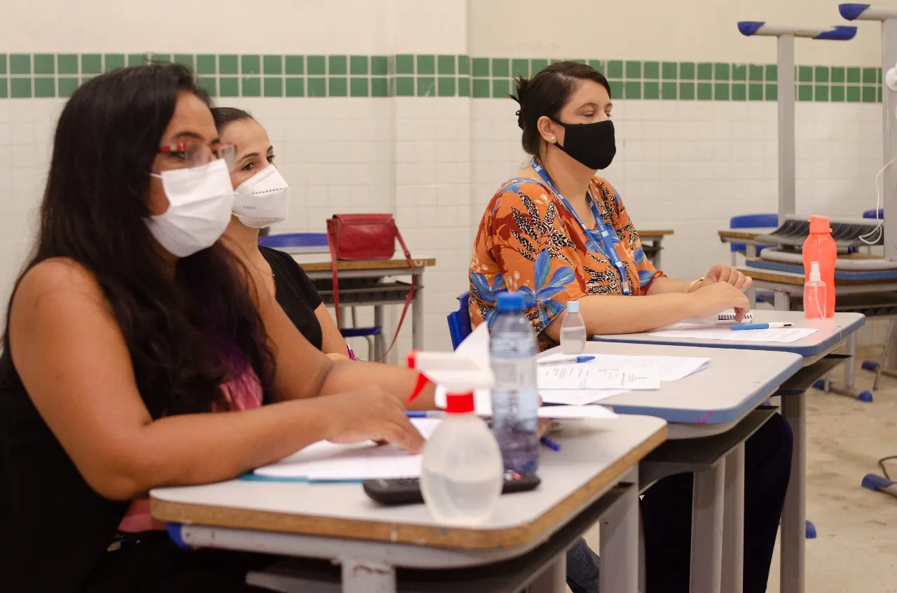 Candidatos sentados em carteiras escolares durante a aplicação de prova de concurso público em Campina Grande.