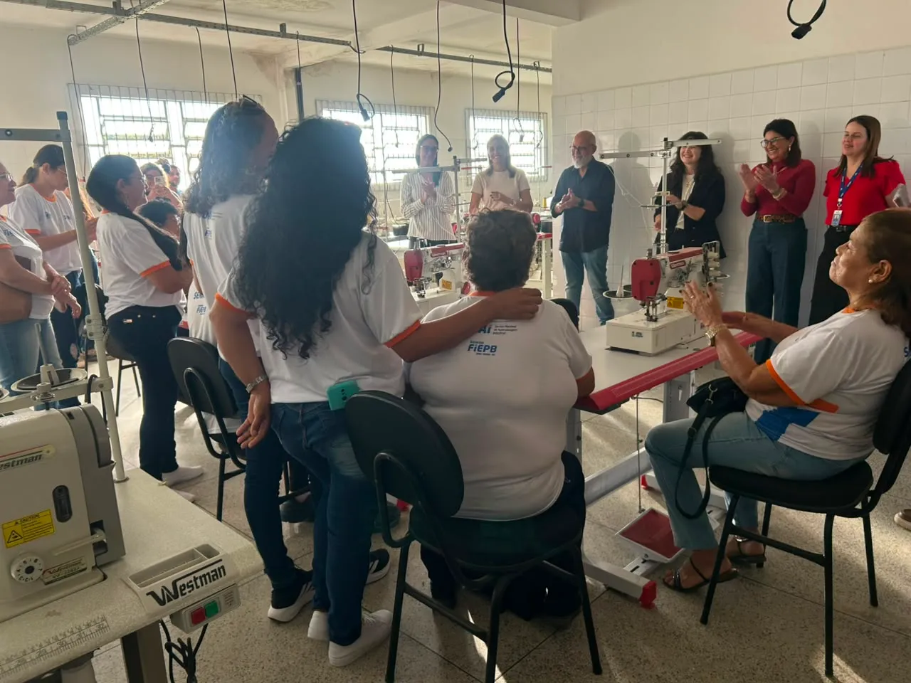 Mulheres atendidas pelos CRAS na sala do curso de corte e costura, com máquinas industriais, em Campina Grande