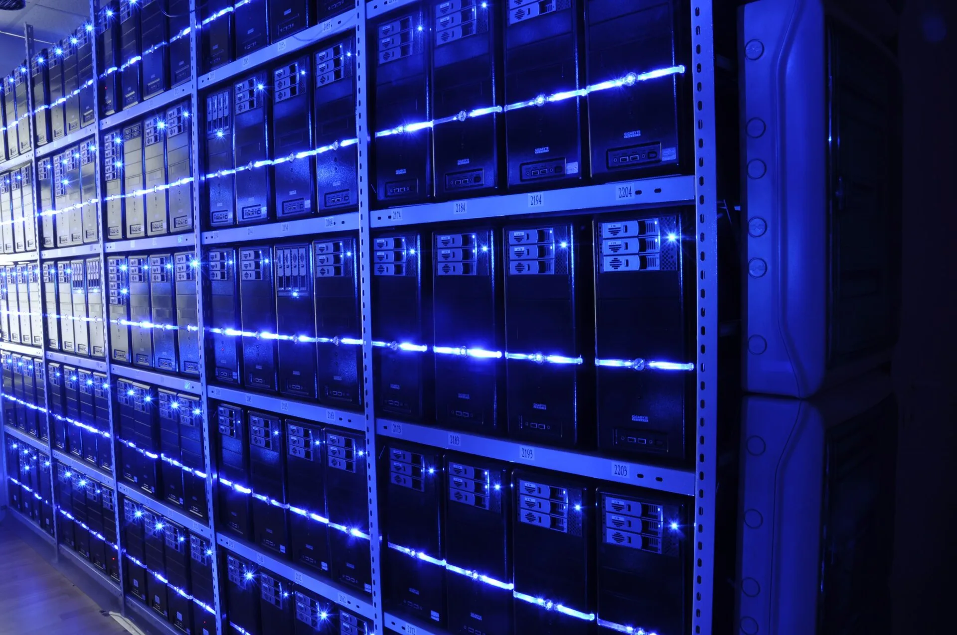 Fileiras de servidores iluminados por luzes azuis em um datacenter.
