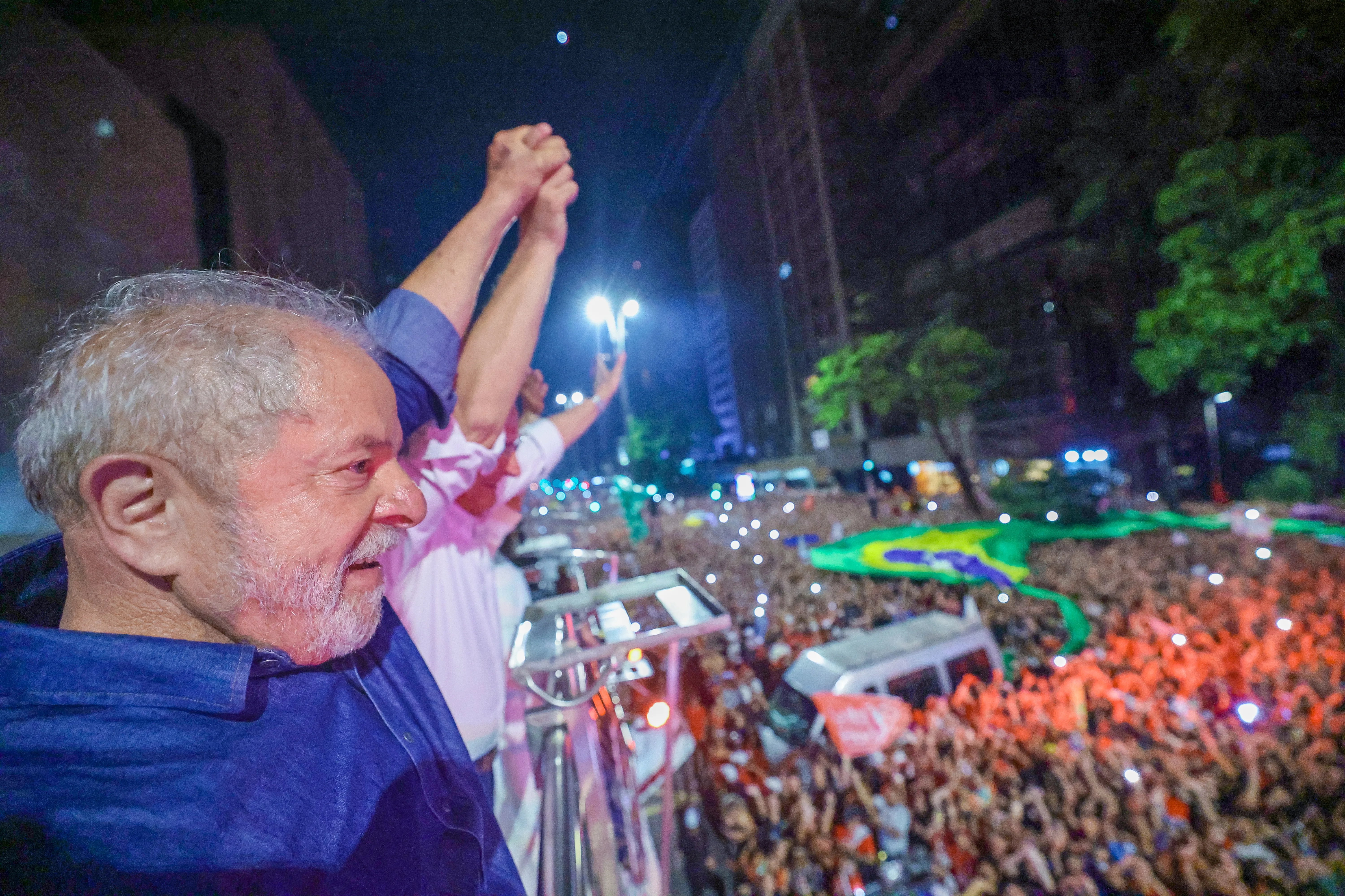 O presidente Lula, de braço erguido, discursa diante de uma multidão na avenida Paulista.