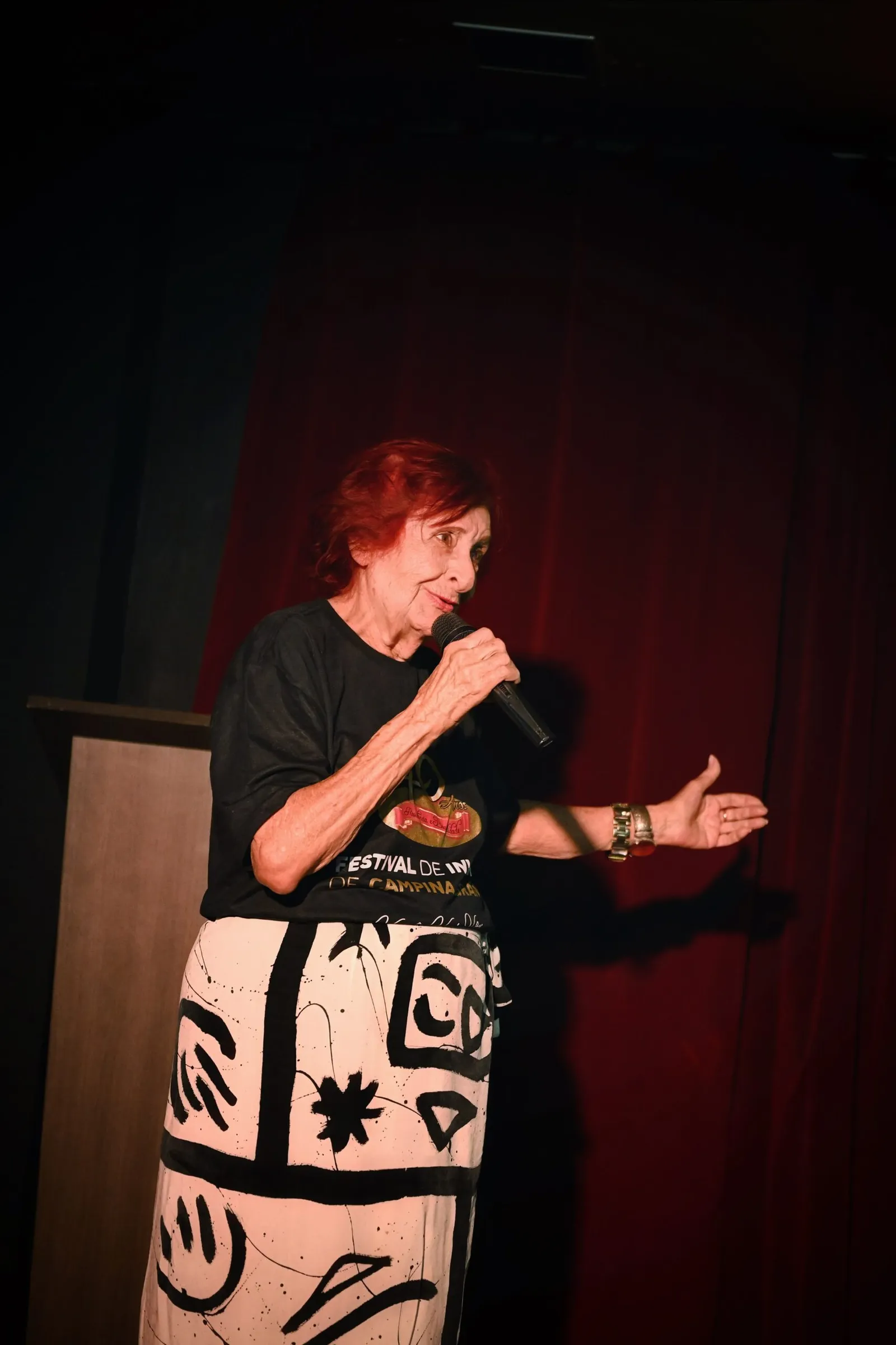 Eneida Agra Maracajá, do Instituto Solidarium, fala ao microfone com a camiseta do Festival de Inverno, no lançamento da 51ª edição