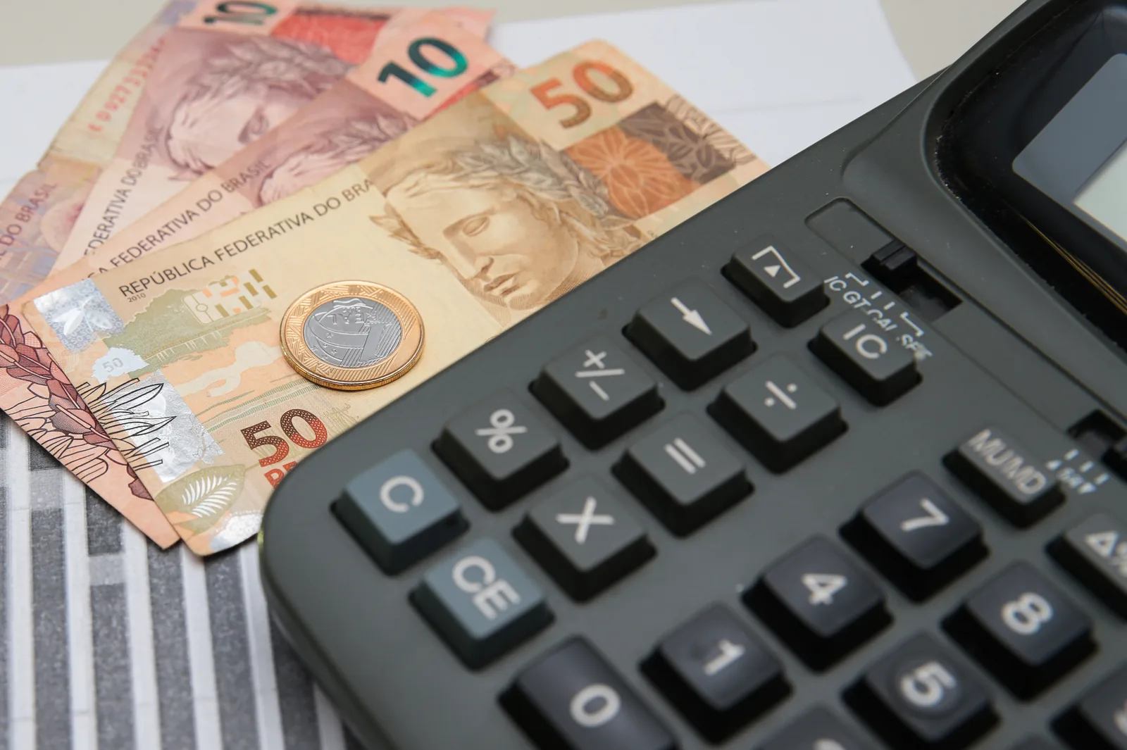 Cédulas de real de diferentes valores sobrepostas, em close, ocupando todo o quadro.