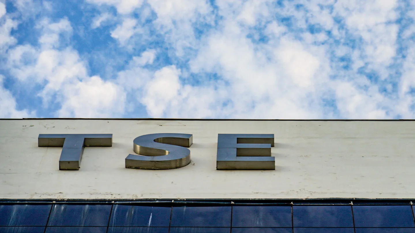 Letreiro metálico com a sigla TSE no alto da fachada do tribunal, contra céu azul com nuvens.