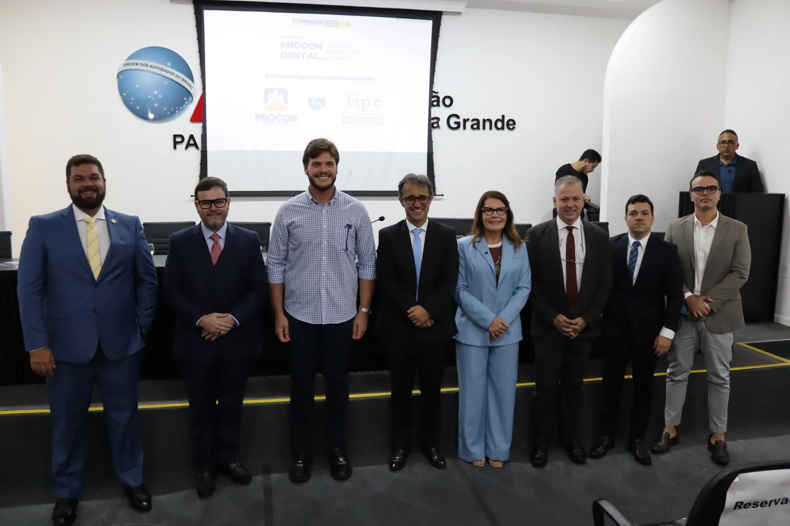 Autoridades perfiladas no palco do auditório da OAB durante o lançamento do Procon Digital em Campina Grande.