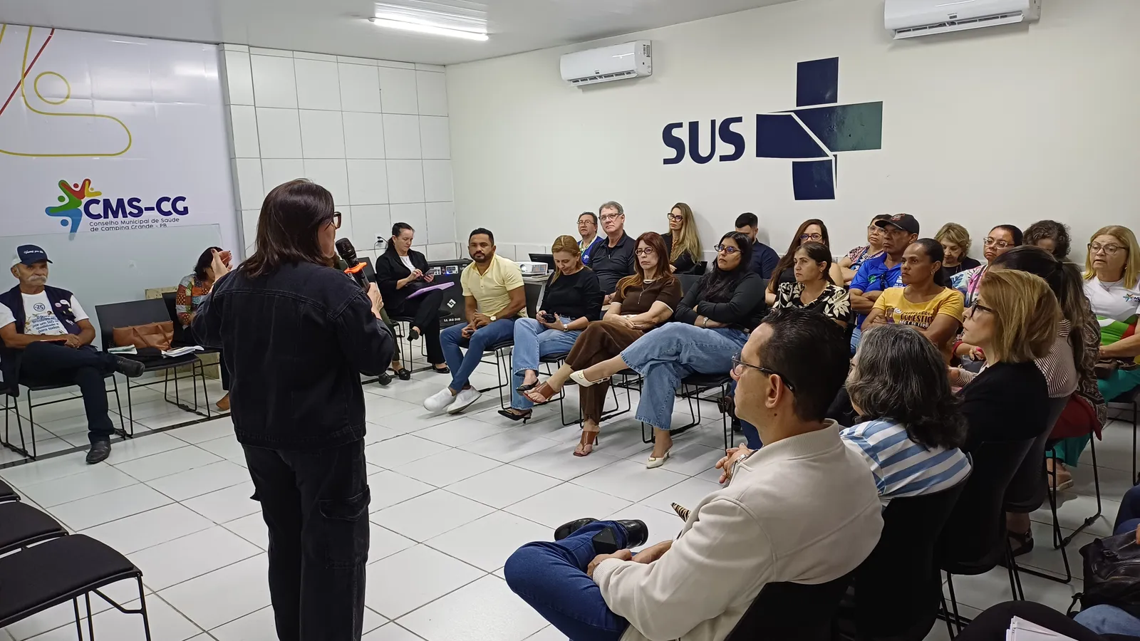 Sessão do Conselho Municipal de Saúde de Campina Grande, com conselheiros reunidos sob os logotipos do CMS-CG e do SUS.